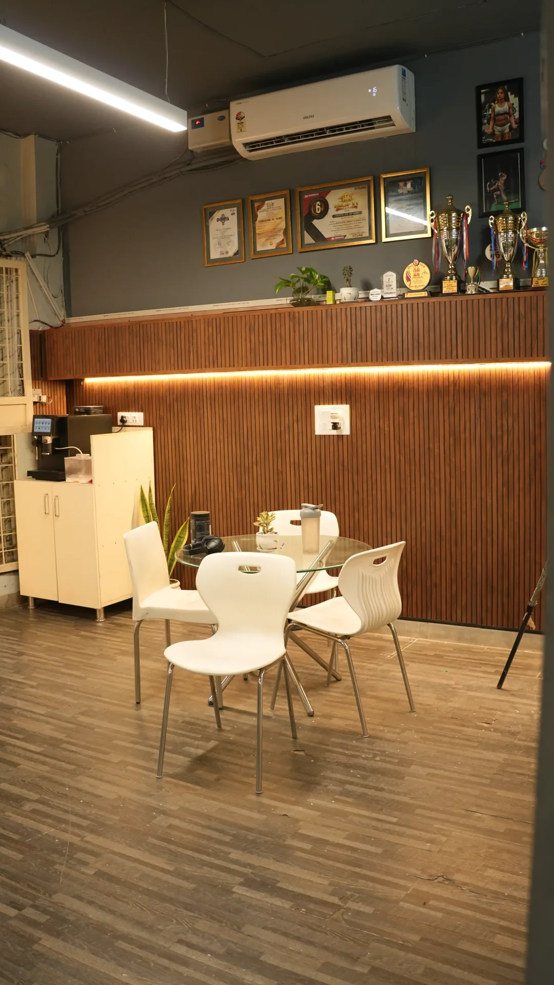 Lounge seating area with coffee machine, certificates, and trophy wall